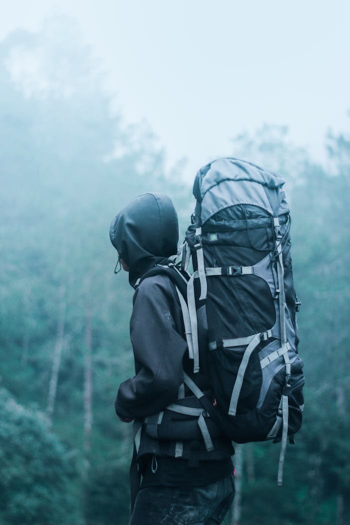 Solo hiker with large backpack in a misty forest, exploring natures serene beauty.